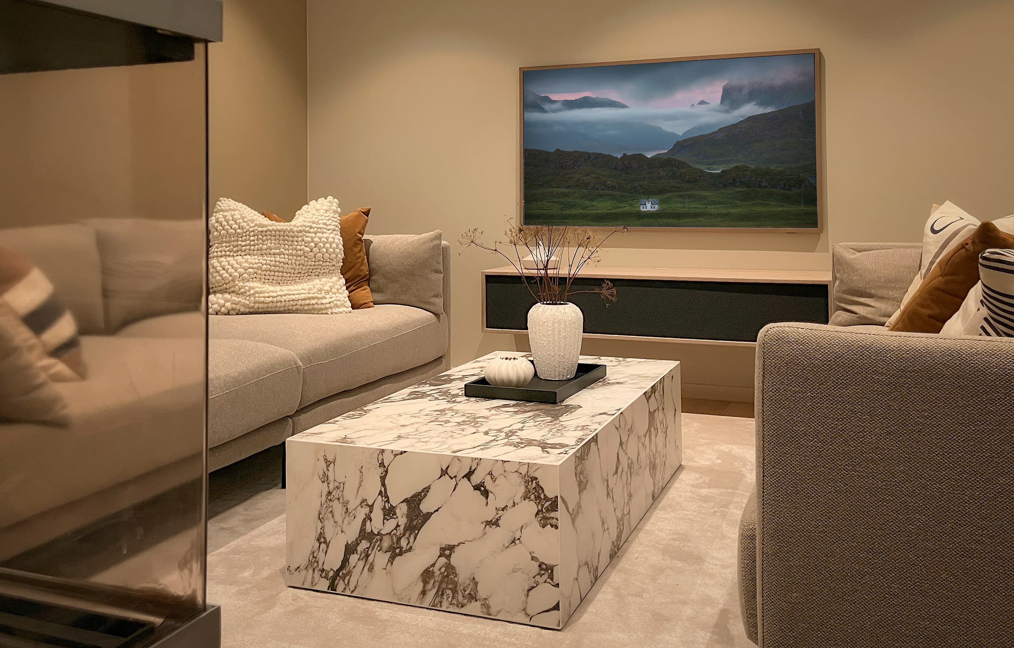 Frame TV wall-mounted above a floating media console with a marble coffee table in front, modern living room
