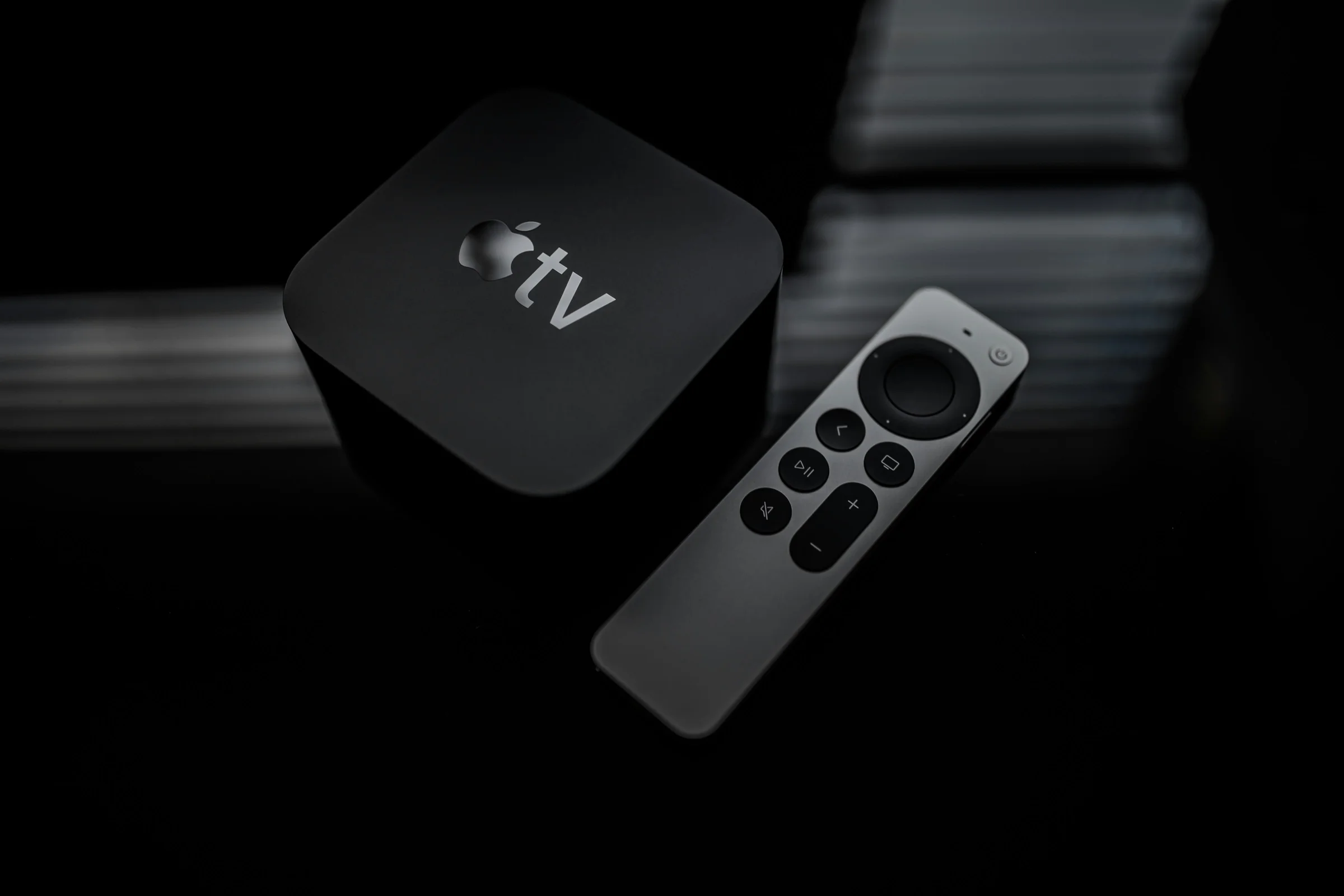 Sleek streaming set-top box and remote shown in low light, emphasizing the remote's buttons