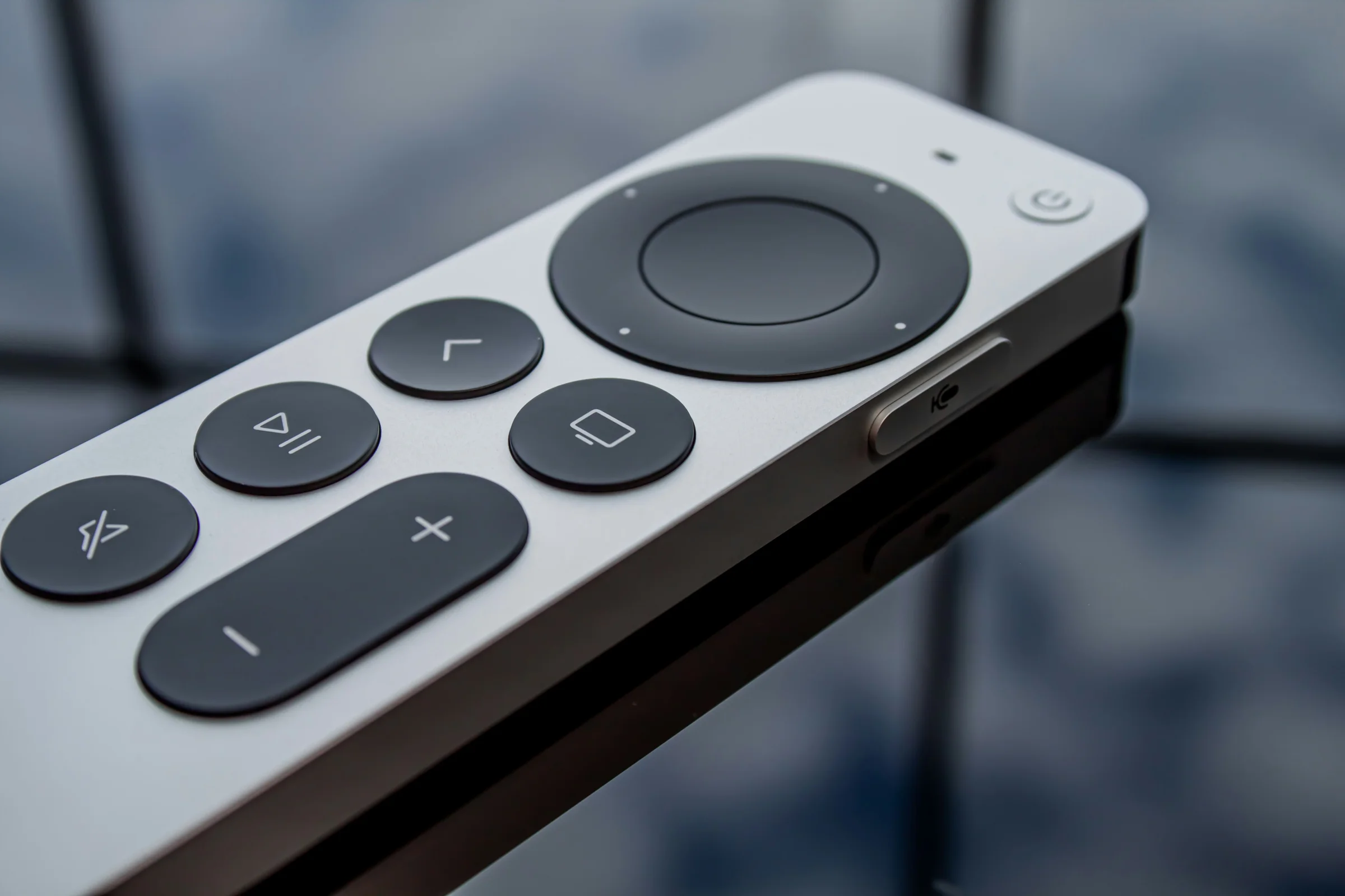 Apple TV remote on a glossy black surface with reflections
